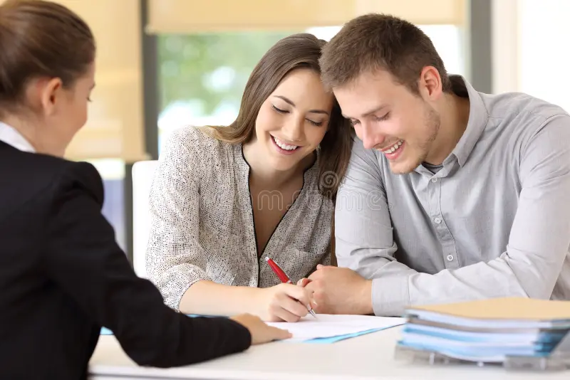 Happy couple signing conventional loan contract in an office